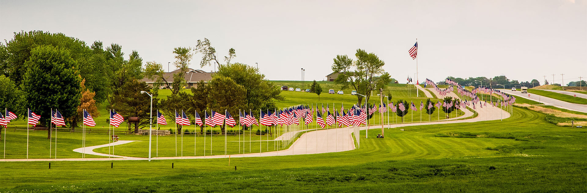 American Flags lining the road with trees in the background 